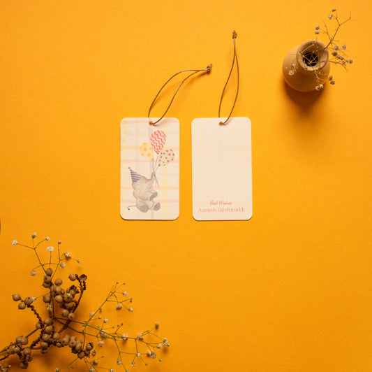 Elphie kids’ hanging tag; a hanging tag with gold elastic with a playful Elephant illustration on a checkered background