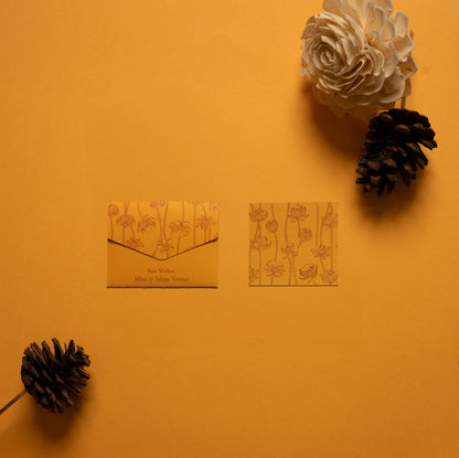 Safira notecard; a card with line drawing lotus pattern on a yellow-orange background paired with a matching small envelope