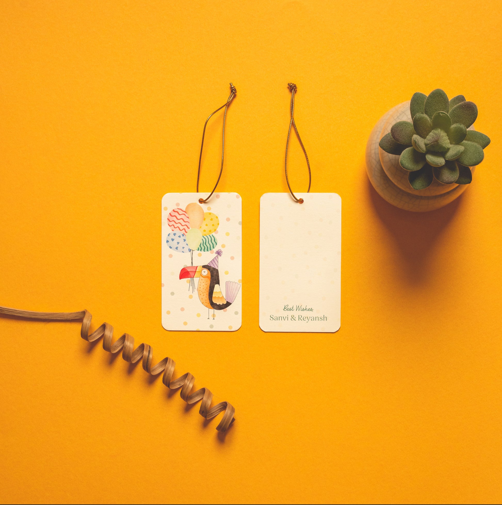 Toco kids’ hanging tag; a hanging tag with gold elastic with a cheerful toucan illustration on a polka dot background