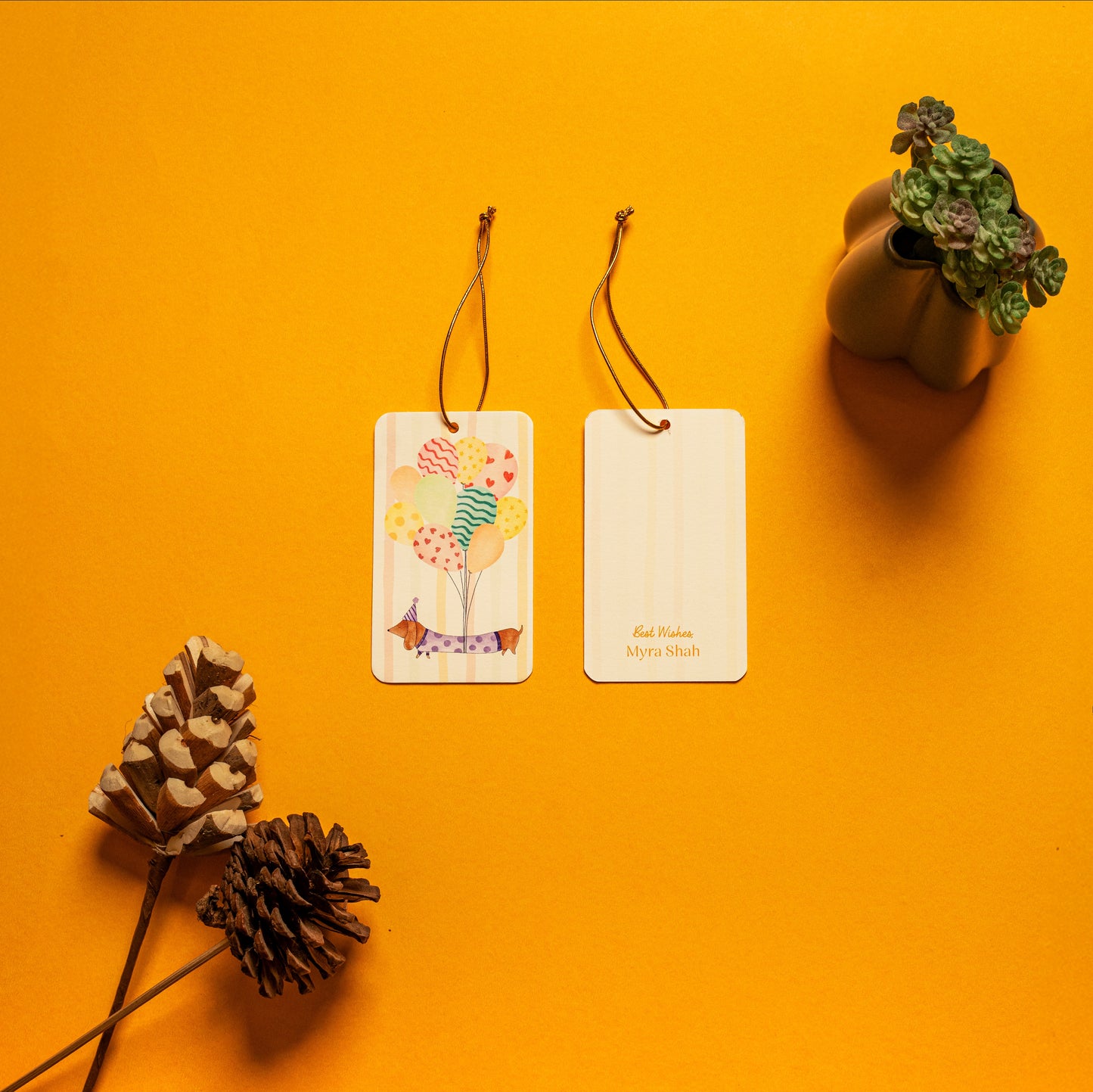 Waggles kids’ hanging tag; a hanging tag with gold elastic with a whimsical dachshund illustration on a stripe background