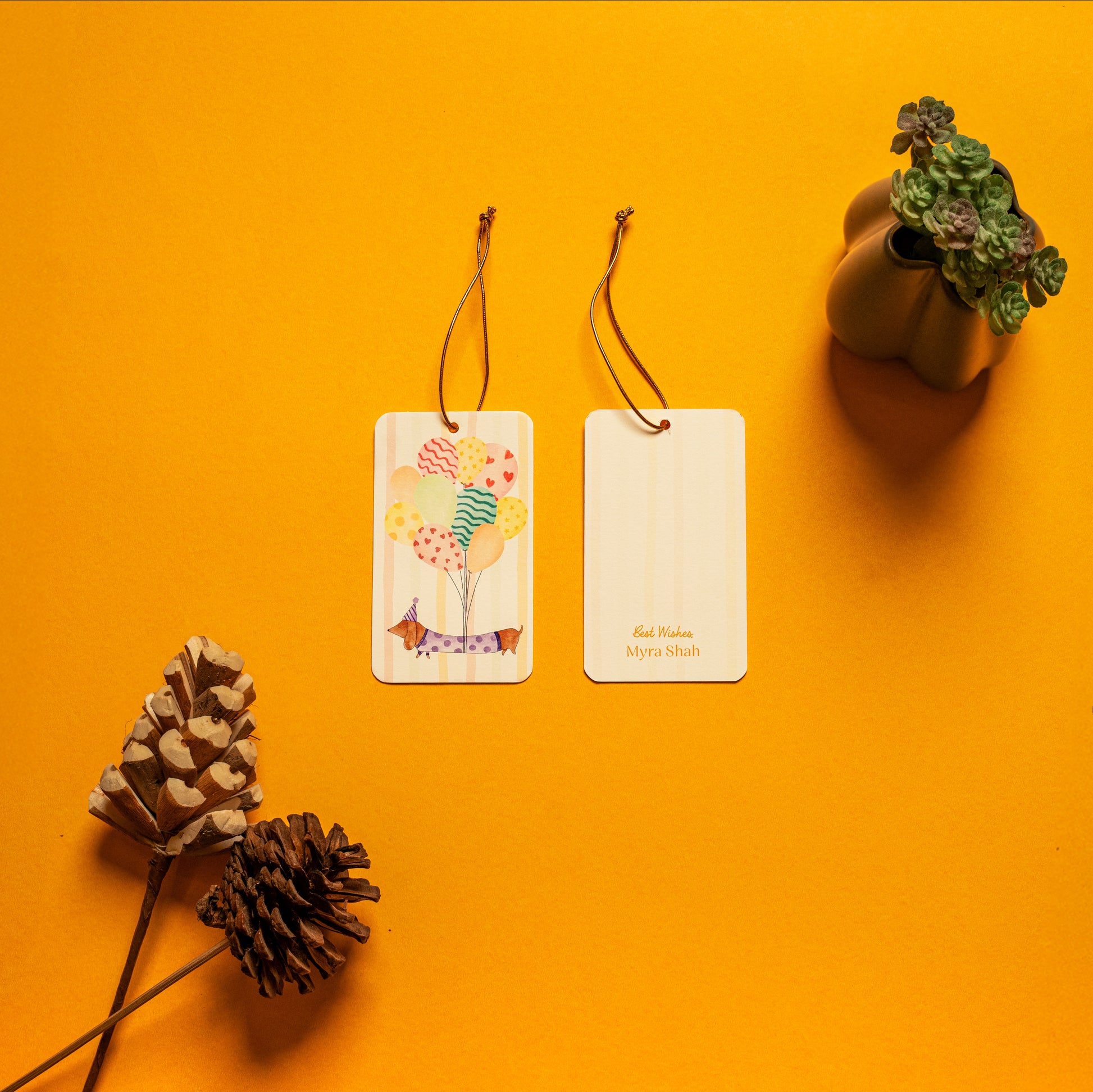 Waggles kids’ hanging tag; a hanging tag with gold elastic with a whimsical dachshund illustration on a stripe background